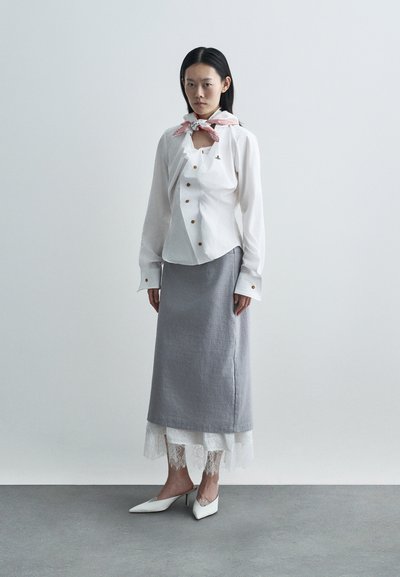 Λευκό πουκάμισο με μακριά μανίκια και χρυσά κουμπιά, ανοιχτό γκρι μακρύ φούστα με δαντελένια φάσα, λευκά παπούτσια ψηλοτάκουνα με μυτερή μύτη και ροζ φουλάρι με μοτίβο γύρω από τον λαιμό.