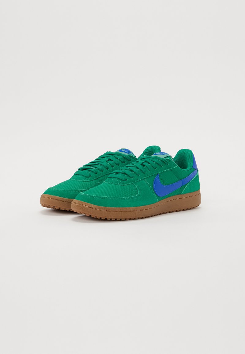 Sneaker verdi in tessuto con dettagli blu e suola in gomma. Presentano un design laccato piatto e una superficie testurizzata.