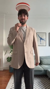 Beige csíkos blézer, hajtókával, egysoros gombos záródással és két első zsebbel. Szürke pólóval és sötét nadrággal viselve. Egyszerű, modern dizájn.