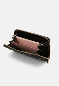 Billetera de cuero negra con un zipper dorado, que cuenta con múltiples compartimentos, incluyendo ranuras para tarjetas de tela rosa y un bolsillo con zipper.