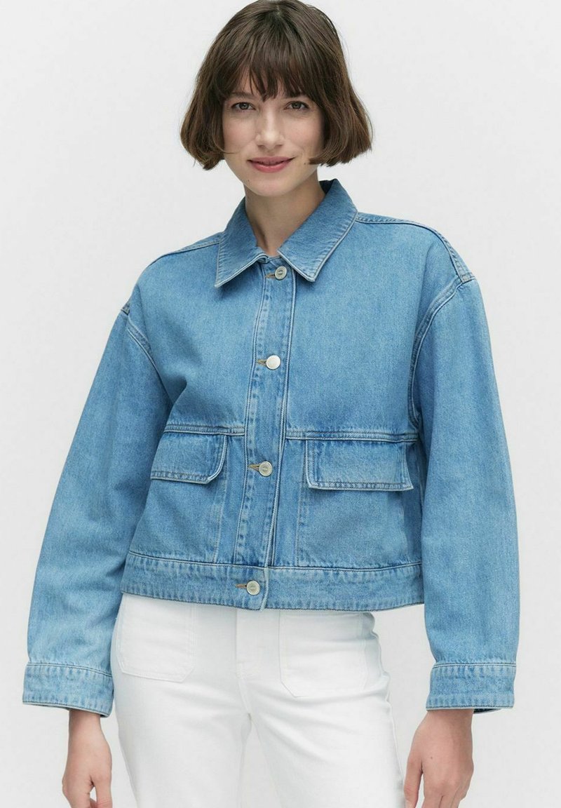 Vaaleansininen denim-takki, jossa on kauluksellinen kaula, etupocketit ja hopeiset napit. Ominaisuuksia ovat lyhyt malli ja rento istuvuus.