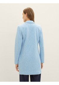 Blue textured coat with long sleeves and a notched collar. The design features a straight cut, reaching mid-thigh, with subtle ribbing.