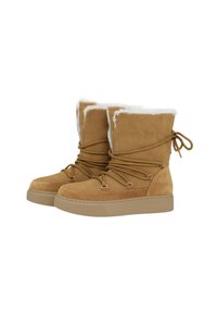 Botas de ante color marrón con forro de suave piel de cordero blanca, punta redondeada, cordones ajustables y suela plana de goma. Presenta ojales decorativos y lazos.