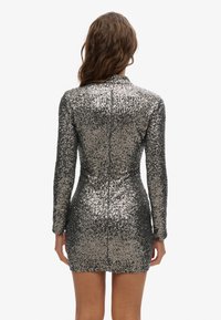 Silberne Pailletten-Minikleid mit langen Ärmeln und hohem Ausschnitt, das eine taillierte Silhouette und einen verdeckten Reißverschluss auf der Rückseite bietet.