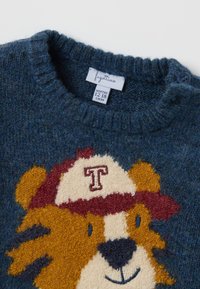Blauwe wollen trui met een ronde hals. Heeft een leeuwontwerp met een baseballpet, textuur-garen, en een label dat maat 12-18 maanden aangeeft.