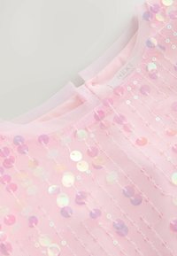 Tissu rose avec des paillettes irisées cousues en lignes verticales et un col en résille avec une petite fente à l'arrière.