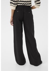 Pantaloni in lino neri a gamba larga con tasche posteriori e dettagli sui bottoni. Tessitura morbida, vestibilità sartoriale e design a vita alta.