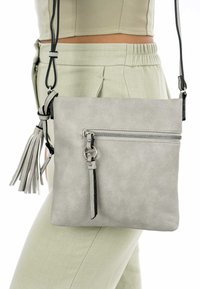 Gray faux leather crossbody bag with a zippered front pocket, tassel detail, and a black strap. Features silver hardware accents.