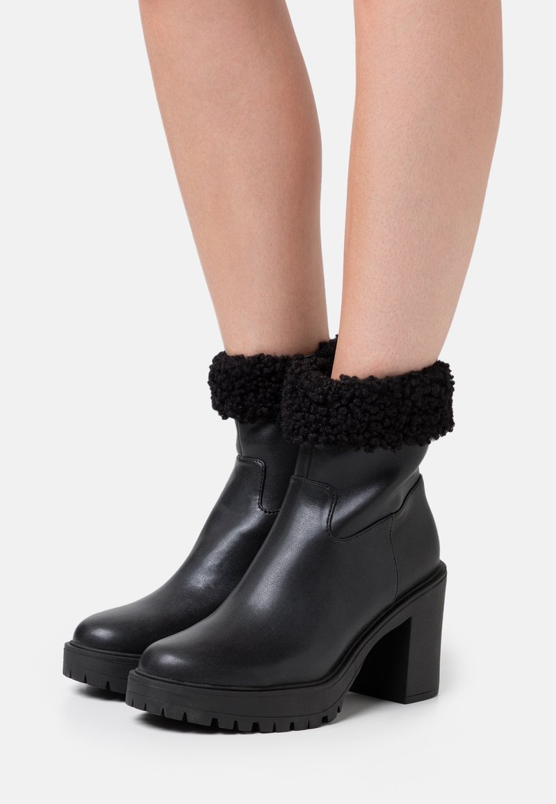 Schwarze Lederstiefeletten mit einer strukturierten, schwarzen Fleeceumschlag, einem klobigen Absatz und einer Gummisohle mit einem Profildesign.