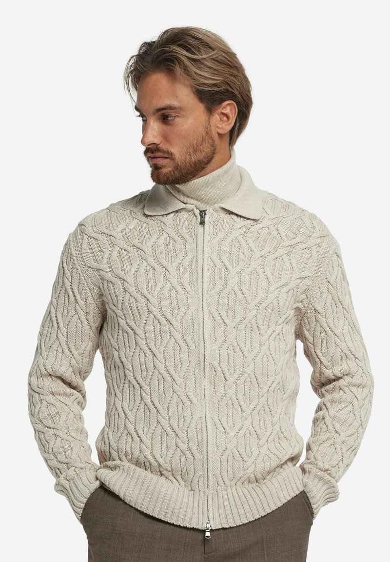 Strickcardigan in hellem Beige mit einem strukturierten Rautenmuster, hohem Kragen und einem Reißverschluss vorne. Rippbündchen und Saum.