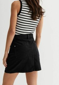 Černá džínsová mini sukně s přiléhavým pasem, dvěma zadními kapsami a mírně áčkovým střihem, doplněná černobílým pruhovaným tílkem.