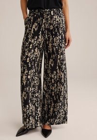 Pantalons à jambes larges en tissu noir avec un motif abstrait crème. Matière légère avec une taille à cordon et des poches latérales.