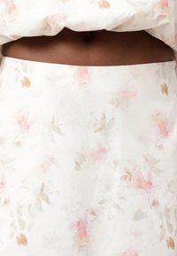 Gonna floreale con tessuto bianco caratterizzato da morbidi motivi ad acquerello rosa e beige, texture liscia e forma sartoriale.