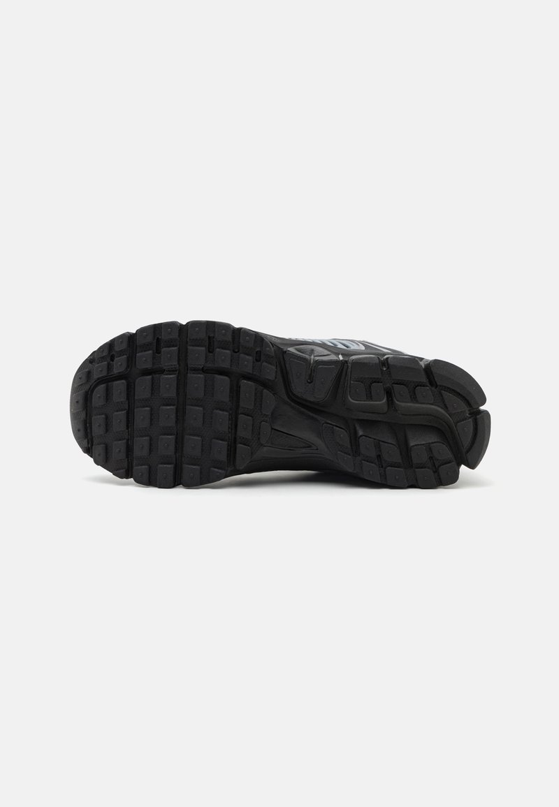 Schwarze Sportschuhsohle aus strukturiertem Gummi, mit tiefen Rillen und einem geschwungenen Design für Traktion und Unterstützung.