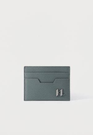 Porte-cartes mince en cuir gris avec surface texturée, plusieurs emplacements pour cartes et un petit logo métallique en bas à droite à l'avant.