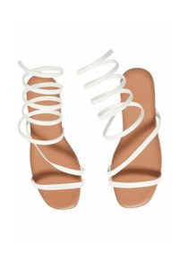 Sandali bianchi con cinturini intrecciati, design aperto sulla punta, soletta piatta color tan, texture liscia, estetica minimale e silhouette elegante.