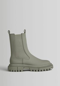 Zielone botki za kostkę z solidnym gumowym cholewką, elastycznymi bokami i szorstką, teksturowaną podeszwą z głębokimi nacięciami zapewniającymi przyczepność.