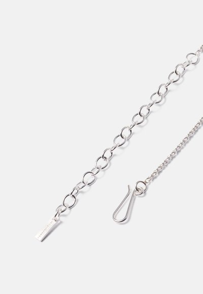 Ασημένια αλυσίδα με ωοειδή κούμπωμα, μια μικρή ορθογώνια ετικέτα με χάραξη και ένα στριφτό τέλος αλυσίδας με κούμπωμα γάντζου.