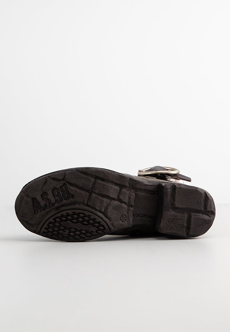 Sandale en cuir noir avec une semelle en caoutchouc texturé. Présente une boucle en argent et un logo en relief sur la semelle extérieure. Design plat avec bout ouvert.