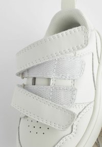 Witte sneaker met een textuurleer bovenwerk, stoffen klittenbandstraps en geperforeerde détails op de neus. Rond model met een gevoerde binnenkant.