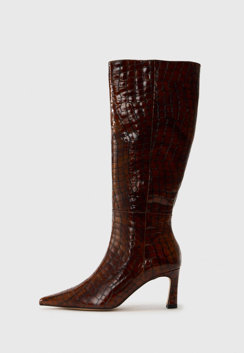 Botte à genoux en cuir d'alligator brun avec un bout pointu, un talon fin et une finition texturée, présentant une surface brillante et des coutures minimales.
