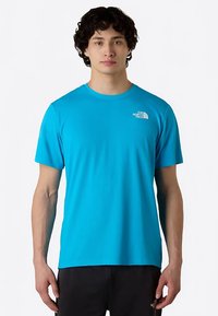 Camiseta de manga corta en azul brillante, confeccionada con tela ligera. Presenta un pequeño logo blanco en el pecho izquierdo. Textura suave, corte regular.