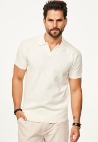 Herren Polo-Pullover mit kurzen Ärmeln in Creme, strukturiertem Muster, V-Ausschnitt, geripptem Kragen und Bündchen, taillierter Schnitt.