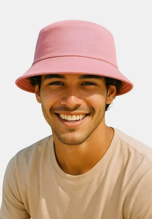 Pink bucket hat made of textured fabric with a wide brim. Features a smooth finish and a structured top. Worn by a smiling individual.