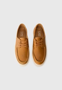 Zapatos de cuero marrón con una textura suave, que cuentan con cordones y detalles de costura, y una suela de goma blanca en contraste.