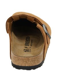 Brun ruskind slide sandal med en kork-fodbund og sort gummisål. Har et justerbart metalspænde for optimal pasform.