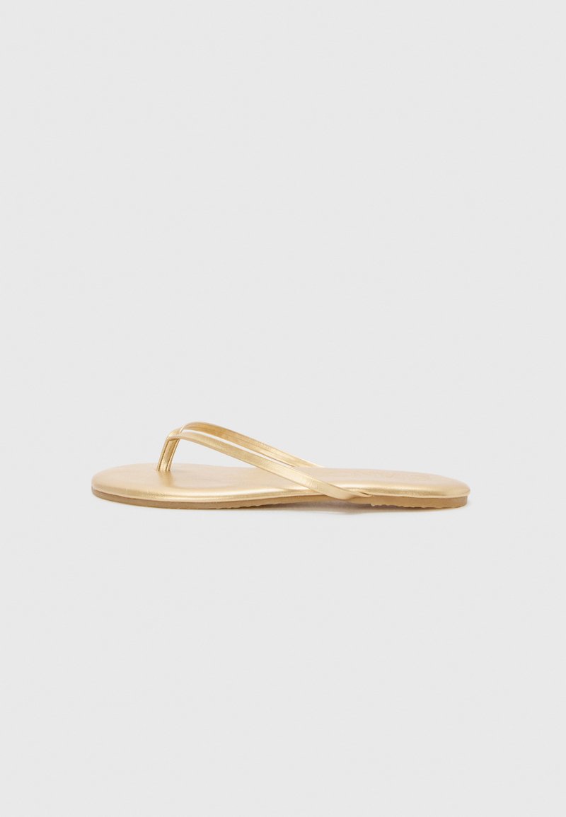 Gold flip-flop sandal with a thin strap design. Flat sole and smooth texture, featuring a simple, minimalist aesthetic.