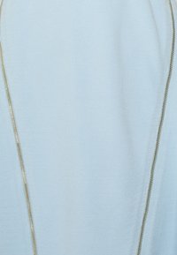 Světlomodrá látka s hladkým povrchem má po straně stříbrný zip, což vytváří moderní designový prvek.