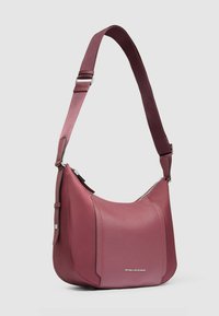 Schultertasche aus tief bordeauxrotem Leder mit glatter Textur; verfügt über einen Reißverschluss und einen verstellbaren Riemen mit geometrischem Muster.