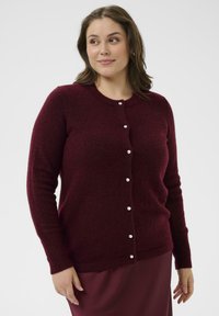 Burgundski cardigan iz mehkega pletenega blaga, z dolgimi rokavi, okroglo ovratnico in malimi belimi gumbi spredaj.