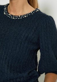 Dark blue knitted sweater with a ribbed texture and short sleeves, featuring a pearl-embellished round neckline.