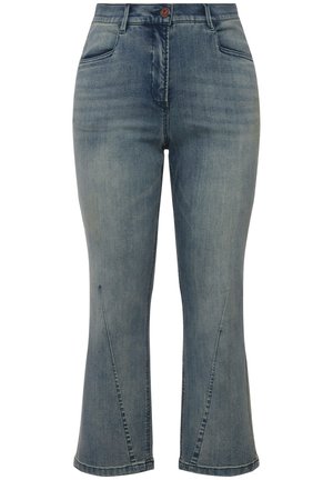 Jean en denim bleu moyen, avec une taille haute, des jambes évasées, des coutures visibles et des coutures diagonales au niveau des genoux, avec un fermoir à bouton rouge.