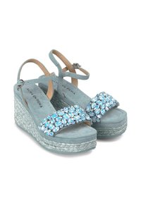 Sandali wedge in suede blu chiaro con una suola intrecciata testurizzata, caratterizzati da una larga fascetta decorata con accenti di gemme blu e trasparenti.