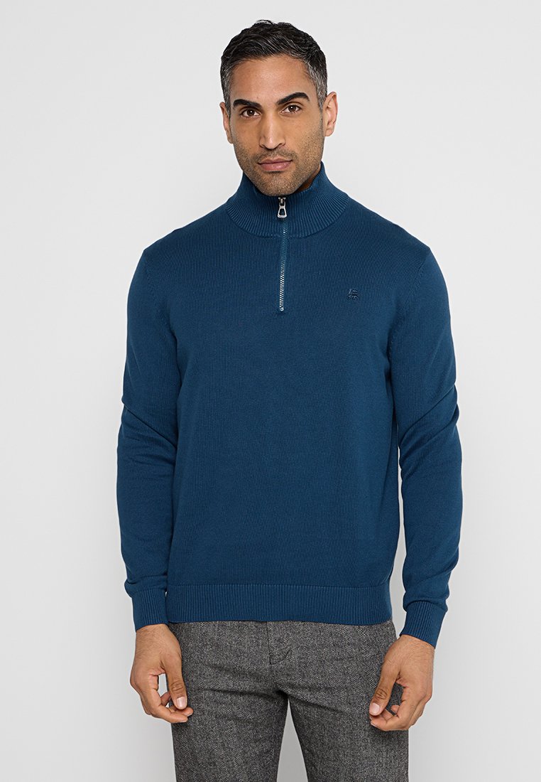 Męski ciemnoniebieski sweter z prążkowanej dzianiny z wysokim kołnierzem i półzamkiem, z dyskretnym logo na klatce piersiowej i fakturowanym materiałem.