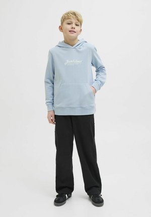 Felpa con cappuccio azzurra chiara, dotata di tasca frontale e testo del logo bianco, abbinata a pantaloni neri e sneaker nere. Design casual.
