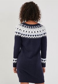 Abito maglione a maglia blu navy con un colletto bianco peloso a motivo, caratterizzato da disegni geometrici e maniche lunghe, di lunghezza a metà coscia.