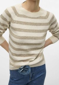Leichter Pullover mit cremefarbenen und beigen horizontalen Streifen, Rundhalsausschnitt und gerippten Ärmelbündchen, kombiniert mit blauen Jeans, die mit einer Denim-Blumenakzent versehen sind.