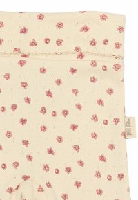 Leggings de corte a la rodilla en un tono beige claro, con un patrón floral de pequeñas flores rosas. Presentan una tela texturizada y una cinturilla acanalada.