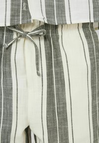 Ensemble de pyjama rayé avec un motif en chevrons en blanc et gris foncé, doté d'une taille élastique et d'un cordon de serrage.