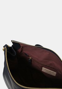 Borsa a tracolla in pelle nera con zip dorata, dotata di un interno in tessuto bordeaux e una tasca interna con zip e etichetta.