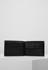 Portefeuille en cuir noir avec plusieurs emplacements pour cartes et un compartiment pour billets, présentant une finition texturée et un branding subtil.