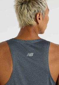 Grijze sportieve tanktop met een mesh-textuur, racerback ontwerp en een reflecterende New Balance-logo op de bovenrug.