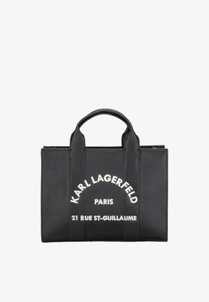 Czarna skórzana torebka z uchwytami u góry z białym napisem "Karl Lagerfeld Paris 21 Rue St-Guillaume" z przodu.