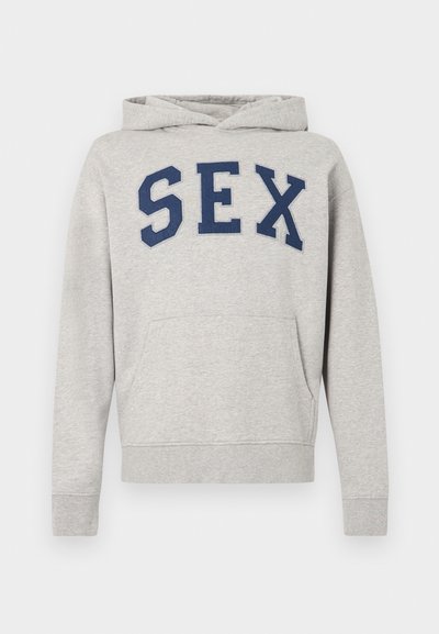 Pilko medvilninio džemperio su gobtuvu su priekiu kišene, ant krūtinės siuvinėtais tamsiai mėlynos spalvos raidėmis „SEX“. Reguliuojamas raištelis gobtuvo krašte.