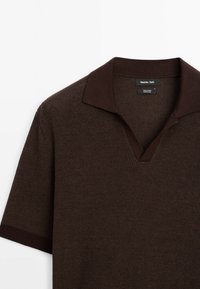 Polo en coton marron avec un tricot texturé, manches courtes et col en V. Présente un col accentué d'un marron plus foncé.