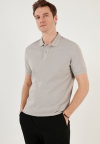 Sivá polo tričko s krátkymi rukávmi a textúrovaným golierom, s dvomi gombíkmi a klasickým strihom. Hladký bavlnený materiál, čistý dizajn.